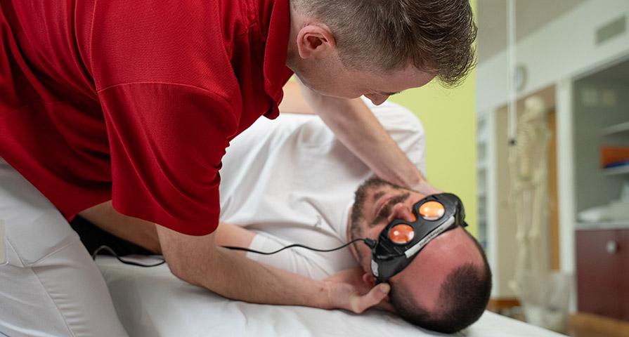 Bild eines Physiotherapeuten und eines Patienten, bei welchem eine spezielle Videobrillen (Videonystagmusbrillen) zum Einsatz kommt.